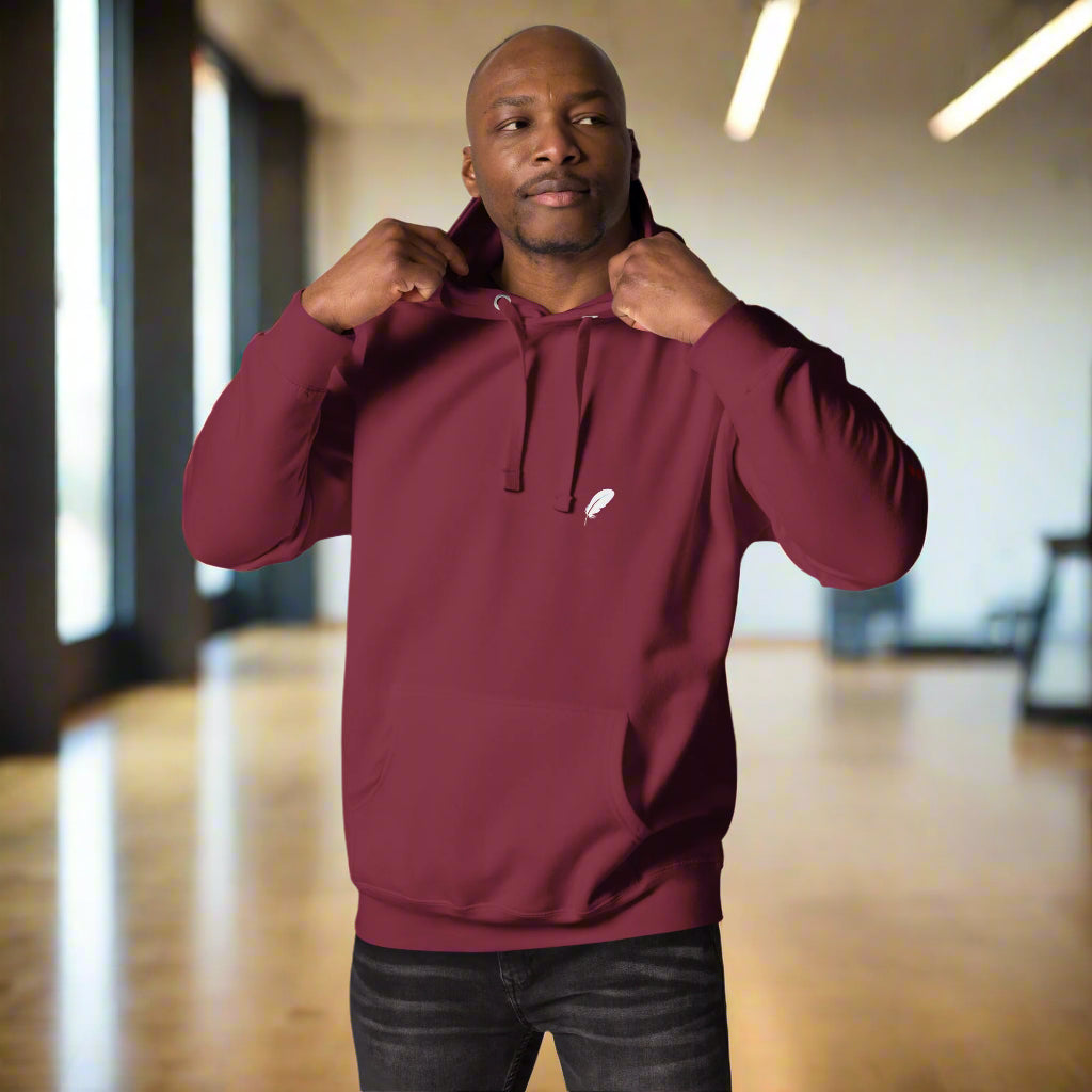 Man wearing a maroon hoodie with a small white logp
