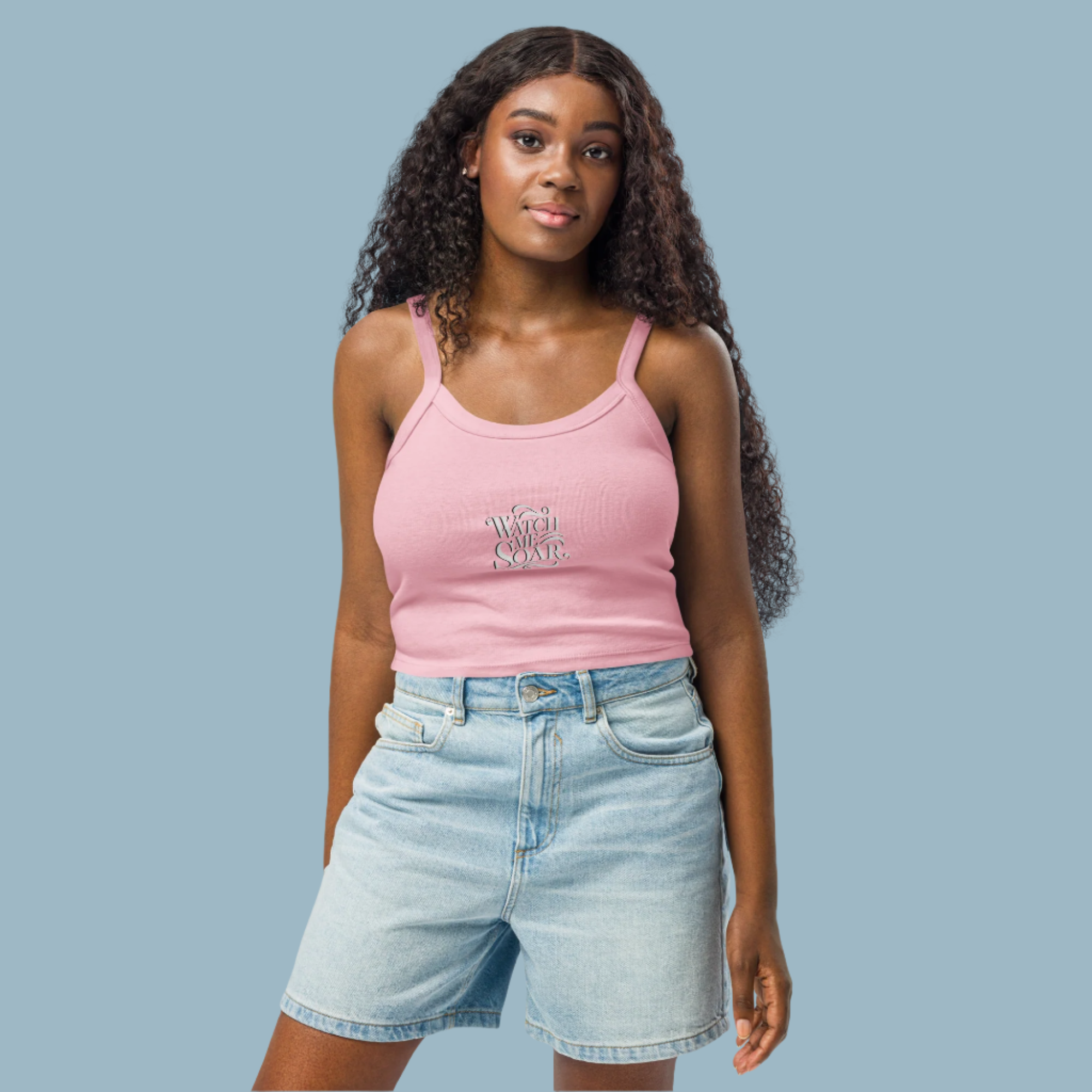 Woman wearing a pink tank top and denim shorts on a white background
